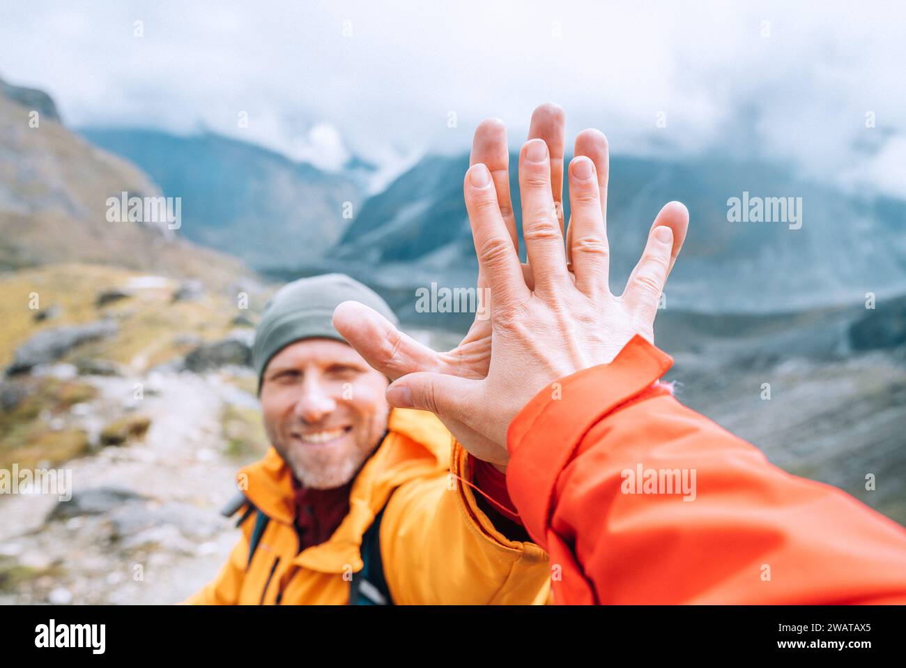 Blouson orange habillé Backpacker souriant donnant High Five à la partenaire féminine pendant le trekking de la vallée de l'Himalaya. Route d'escalade de pic de Mera près du Khare sett Banque D'Images