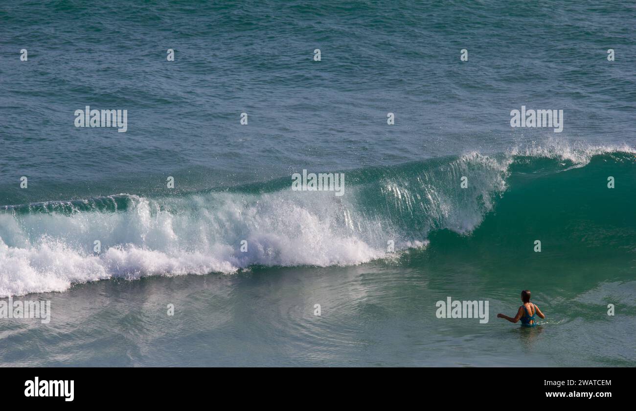 Femme en maillot de bain sur le point de braver le surf à Kynance Cove, Cornwall. Kernow Banque D'Images