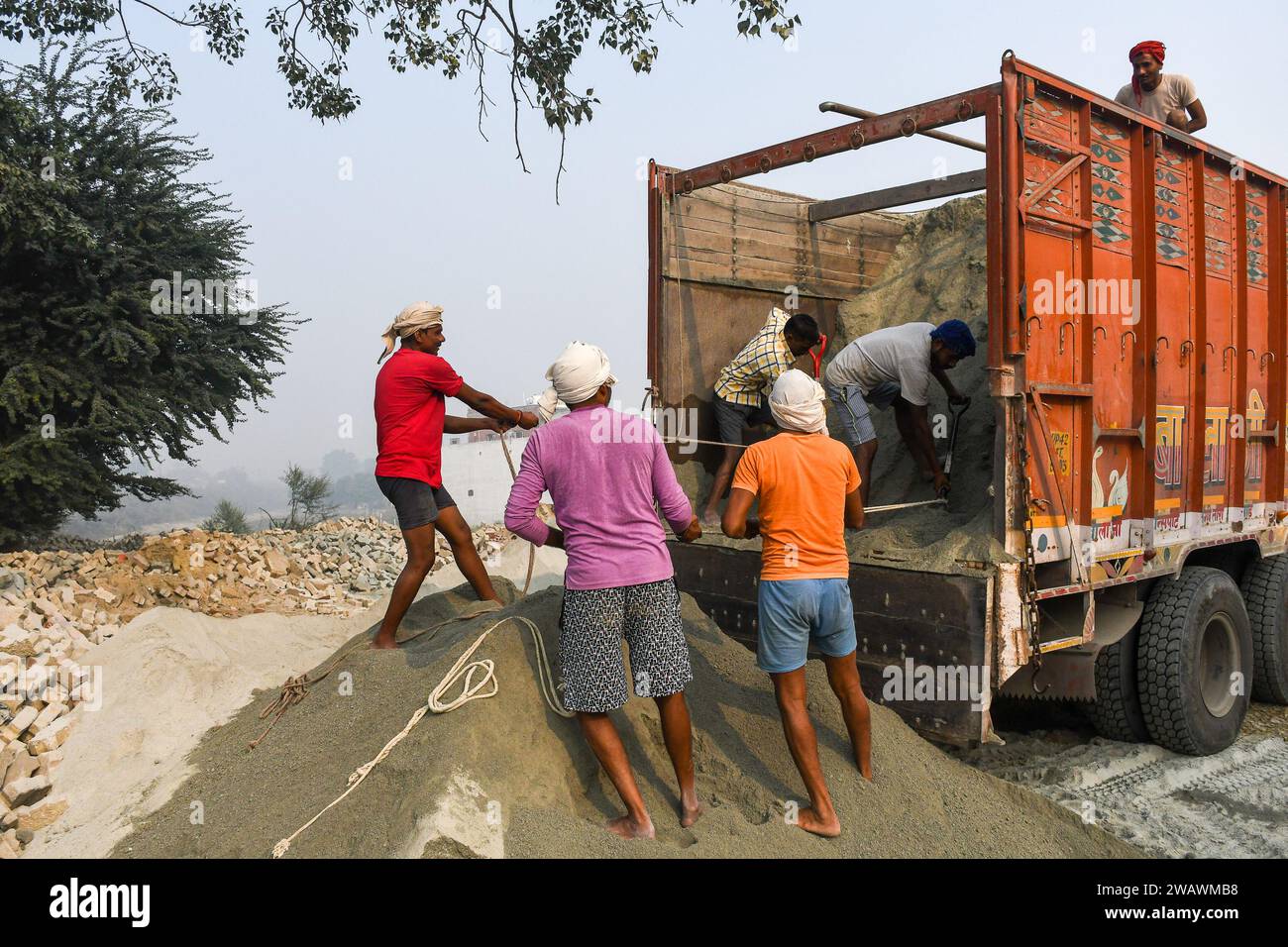 Ayodhya, Inde. 26 décembre 2023. Les ouvriers déchargent le sable d'un camion pour la construction de routes avant l'inauguration du temple RAM. Le temple RAM sera inauguré le 22 janvier par le Premier ministre Narendra Modi et le Premier ministre de l'Uttar Pradesh, Yogi Adityanath. Près de 8 000 dignitaires, dont des voyants, des industriels, des VVIPS, des acteurs et des lauréats du Padam Bushan, ont été invités à ce grand événement. (Photo de Biplov Bhuyan/SOPA Images/Sipa USA) crédit : SIPA USA/Alamy Live News Banque D'Images