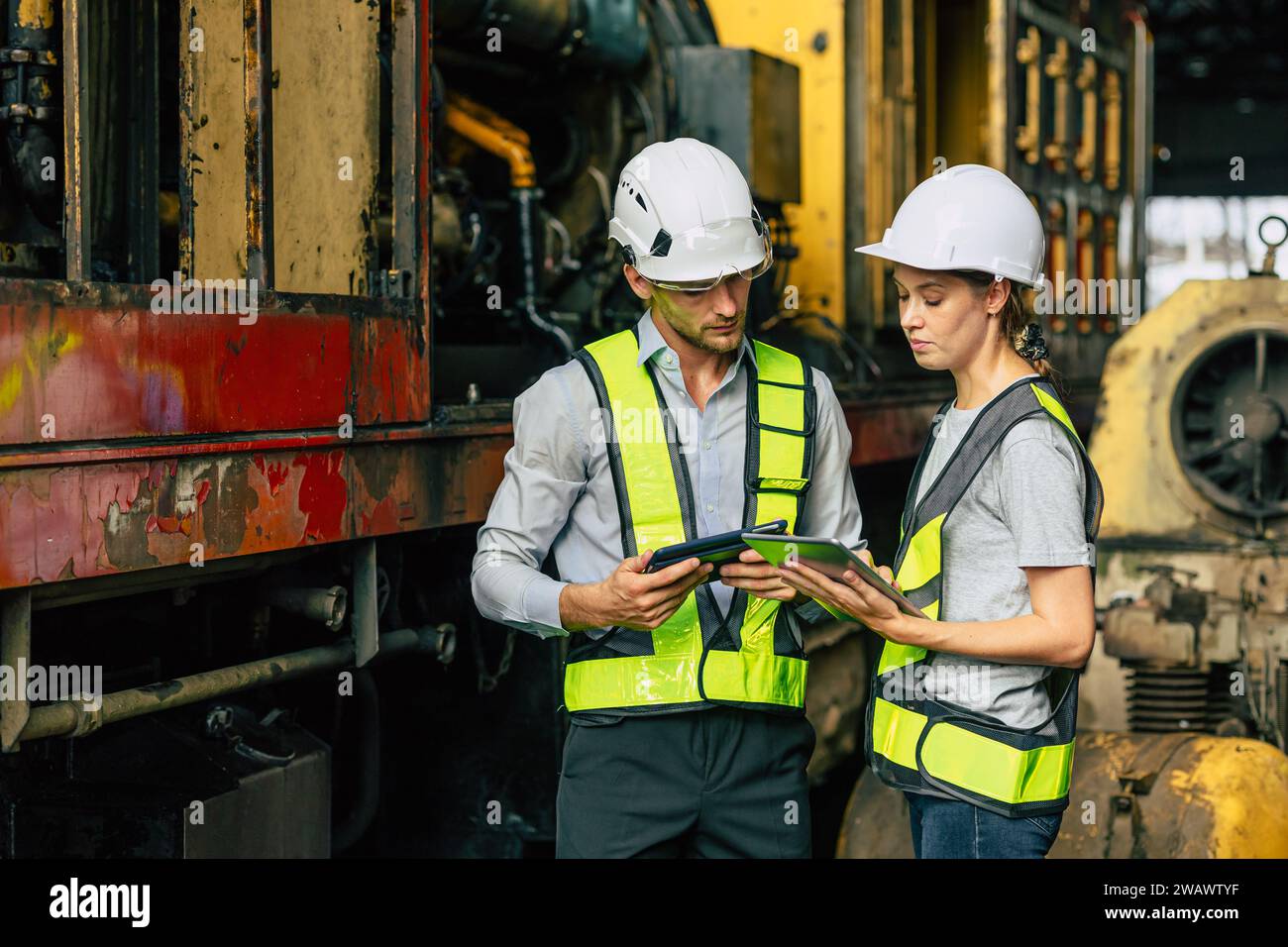 Homme et femmes d'équipe d'officier d'ingénieur travaillant ensemble avec la vérification de tablette inspectent dans l'usine de construction d'industrie lourde. Banque D'Images
