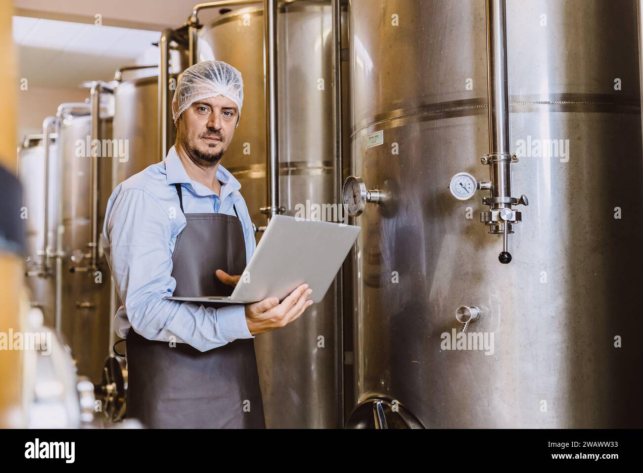 Viticulteur professionnel travaillant dans une grande usine de vinification moderne alcool alcool alcool industrie du contrôle de la qualité et de la fermentation surveillent la couleur vintage à Banque D'Images