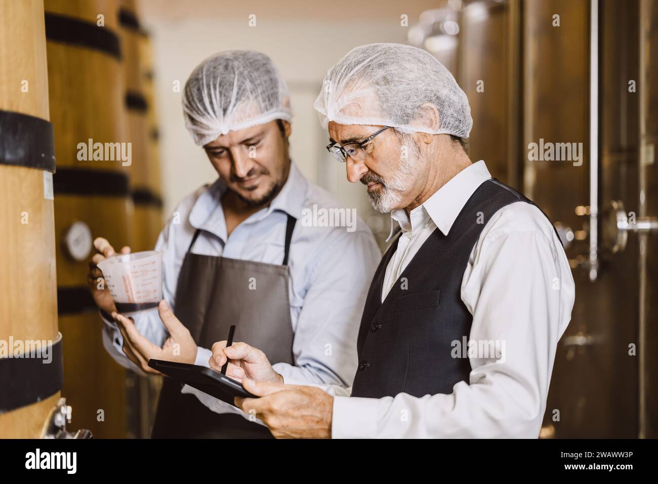 Viticulteur professionnel travaillant dans une grande usine de vinification moderne alcool alcool alcool industrie du contrôle de la qualité et de la fermentation surveillent la couleur vintage à Banque D'Images