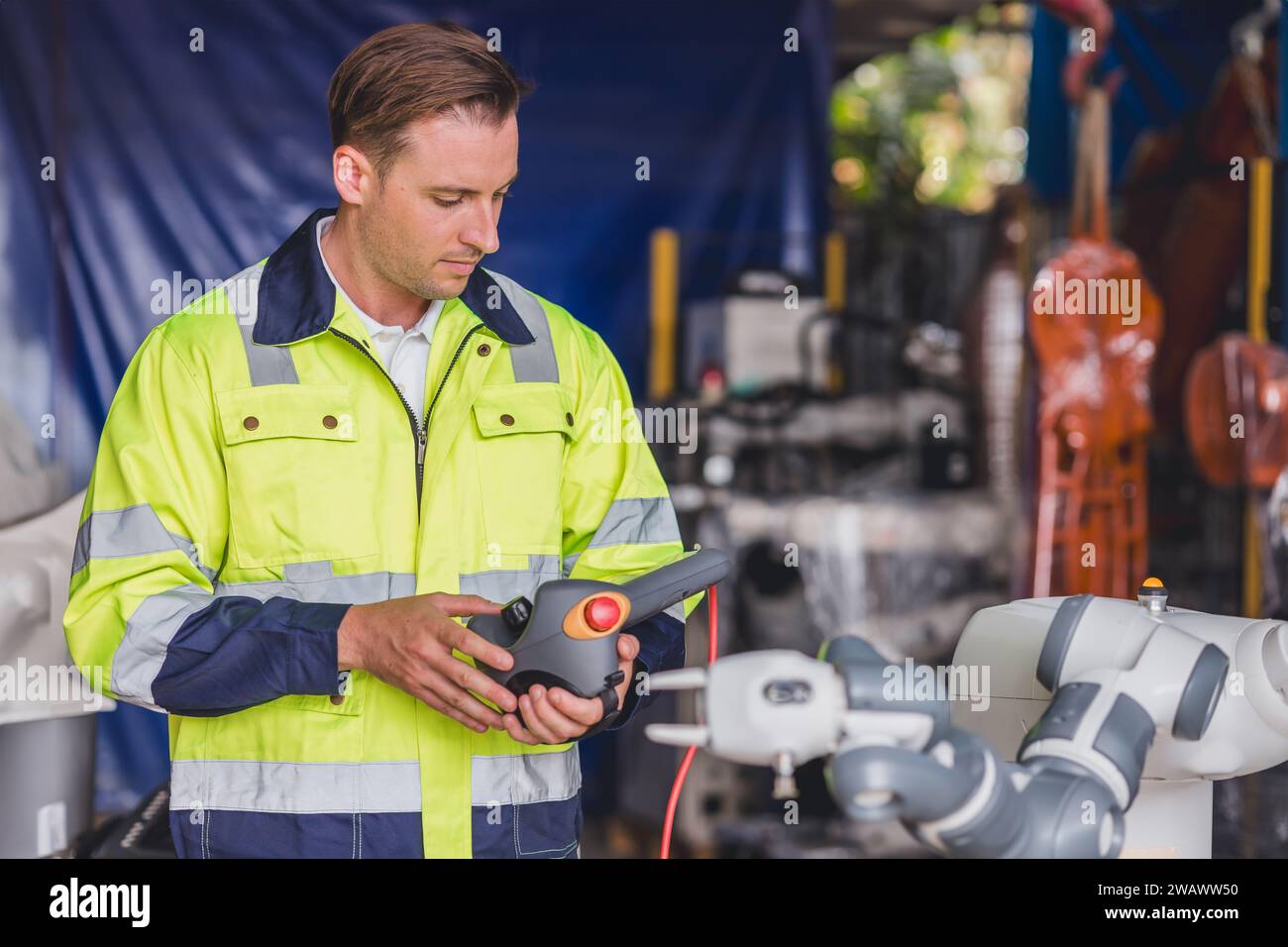 Le contrôle de travail masculin de caucasion d'ingénieur actionne le programme de configuration bras de robot automatique avec la télécommande manuelle manuelle de main Banque D'Images
