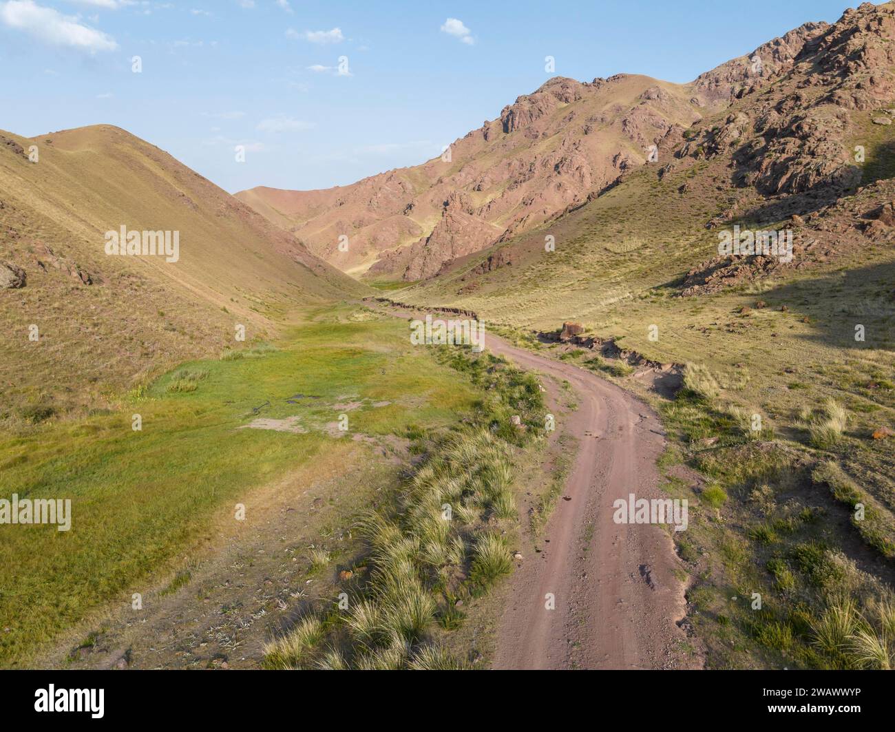 Route de gravier à travers une vallée de montagne, région de Naryn, Kirghizistan Banque D'Images