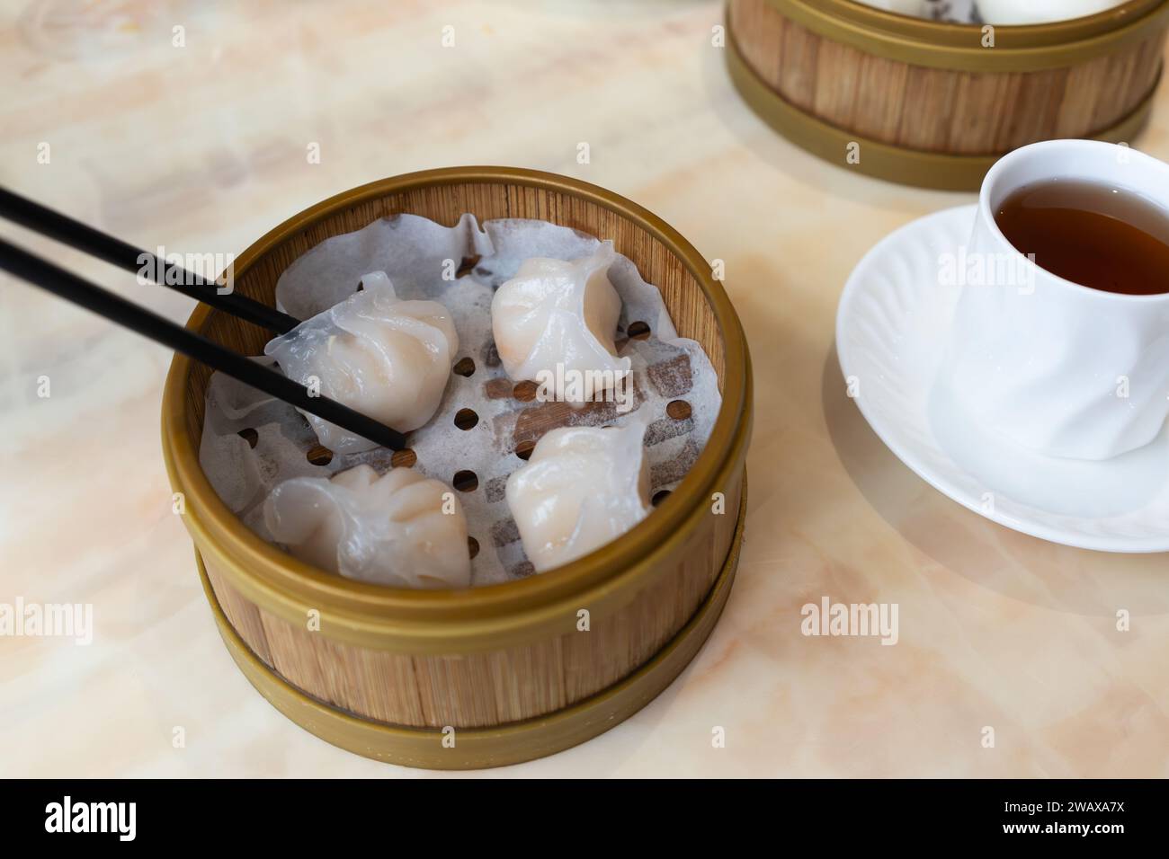 Les dimsum cantonais traditionnels sont ramassés avec des baguettes - ha gow (ou har gow) - boulettes de crevettes servies dans un cuiseur vapeur en bambou, Royaume-Uni Banque D'Images