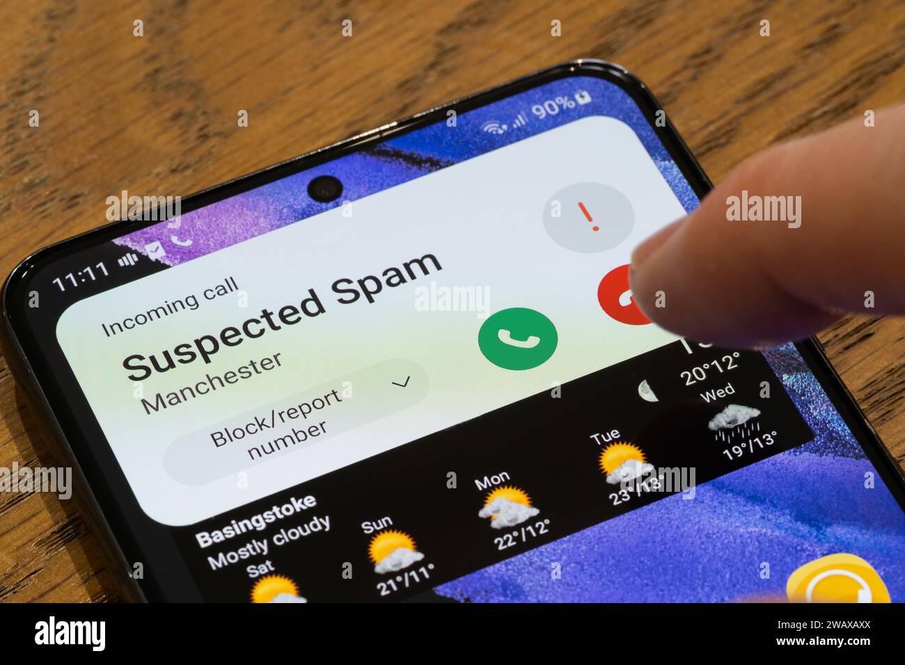 Un écran de téléphone mobile montrant un appel suspect entrant avec un doigt passant au-dessus du bouton raccrocher, Royaume-Uni. Thème : appels à froid, appels gênants Banque D'Images