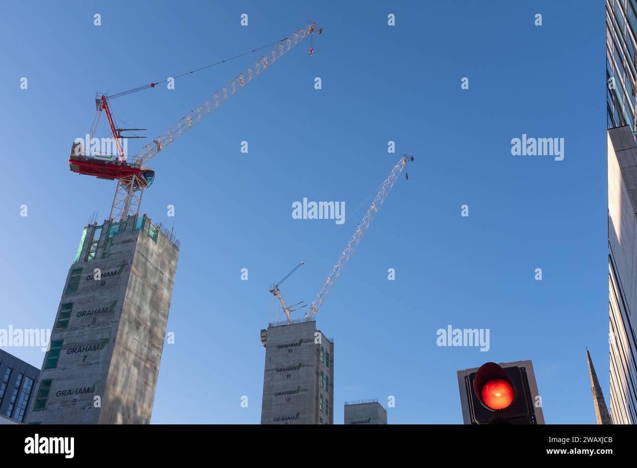 À la recherche de travaux de construction à Bath Street, centre-ville de Glasgow, Écosse. Deux énormes grues se démarquent contre un ciel bleu hivernal brillant. Banque D'Images