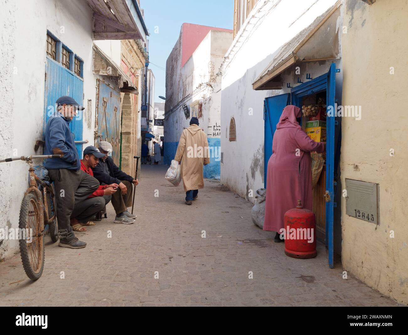 Habitants dans une rue étroite et colorée dans la médina historique de la ville d'Essaouira, Maroc. 7 janvier 2024 Banque D'Images