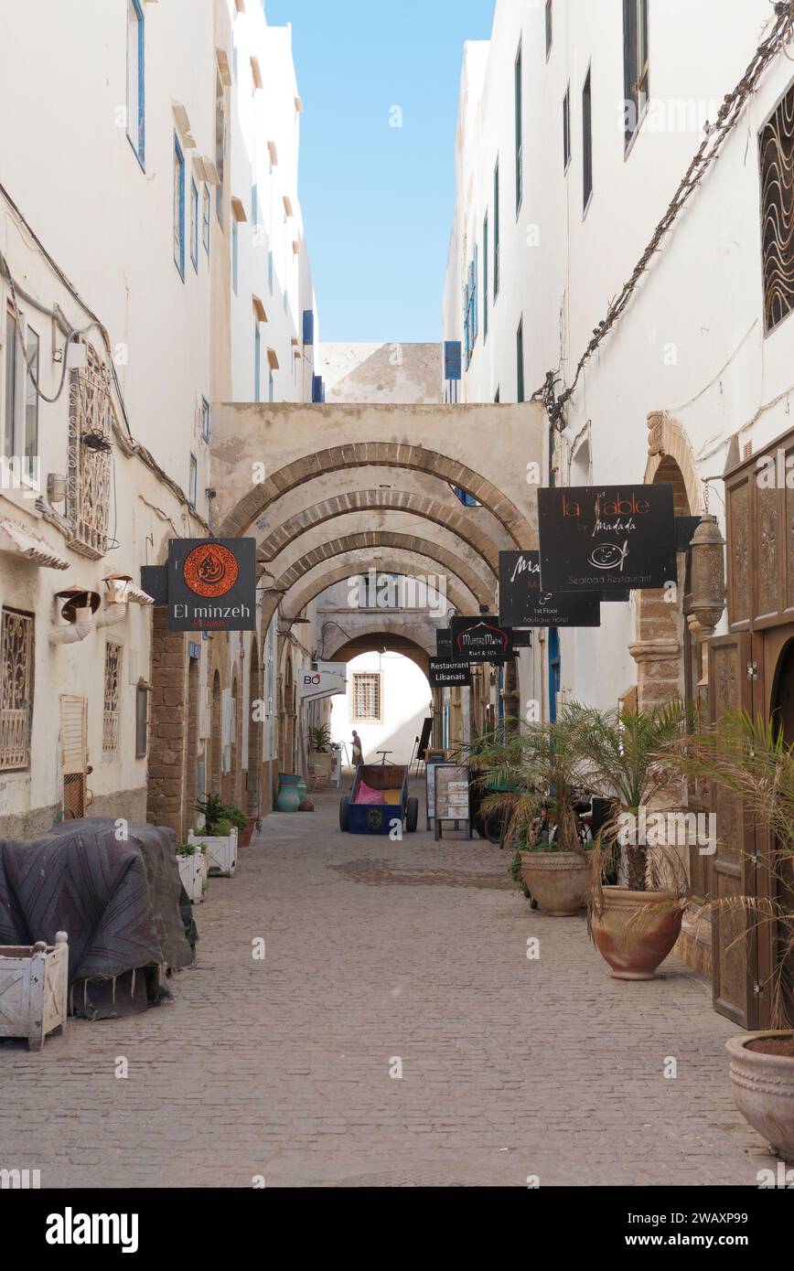 Rue étroite avec des arches, des pots de plantes et un chariot dans la médina historique dans la ville d'Essaouira, Maroc. 7 janvier 2024 Banque D'Images