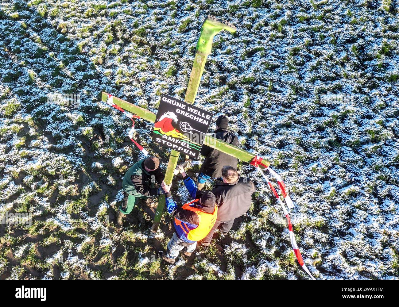 Moormerland, Allemagne. 07 janvier 2024. "Brisez la vague verte, arrêtez les feux de circulation" est écrit sur une affiche du mouvement "Land schafft Verbindung" (LSV) sur une croix avec une botte en caoutchouc au sommet que les agriculteurs érigent. En réponse aux plans d'austérité du gouvernement fédéral, l'association des agriculteurs a appelé à une semaine d'action avec des rassemblements et des rassemblements à partir du 8 janvier. Il devrait culminer par une manifestation majeure dans la capitale le 15 janvier. Crédit : Lars Penning/dpa/Alamy Live News Banque D'Images