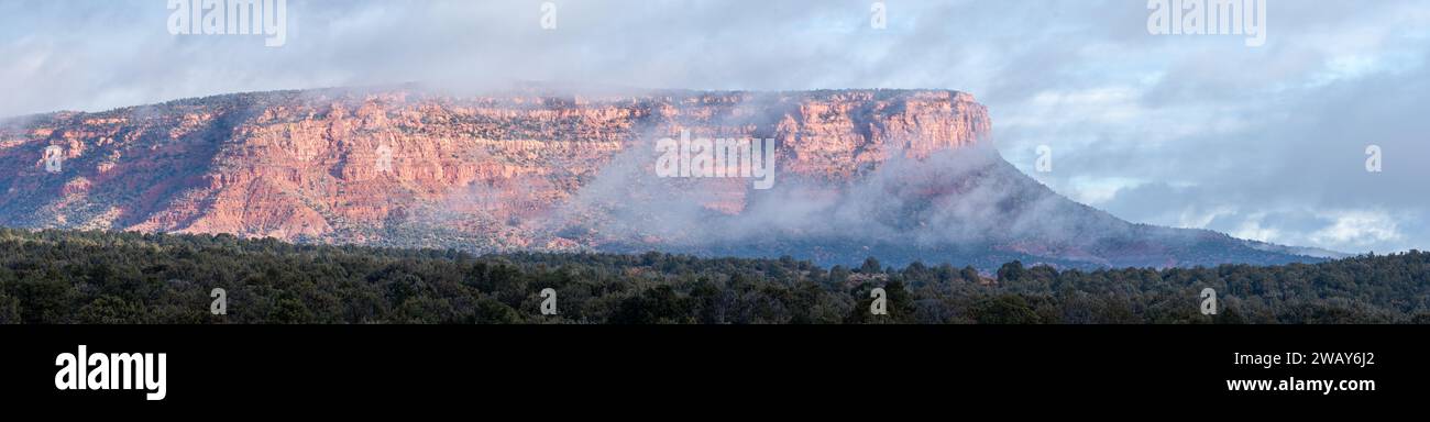 Une image panoramique d'une montagne en arrière-plan, avec un nuage planant dessus, offrant un beau contraste de couleurs contre le paysage Banque D'Images