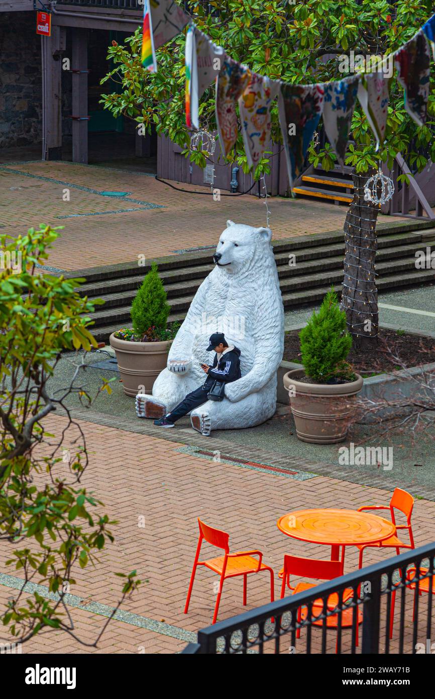 Jeune personne assise sur un ours polaire à Market Square Victoria Colombie-Britannique Canada Banque D'Images