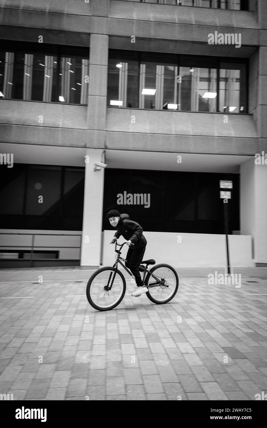 Un jeune cycliste monte son vélo parmi les bâtiments architecturaux de la City of Central London England Banque D'Images