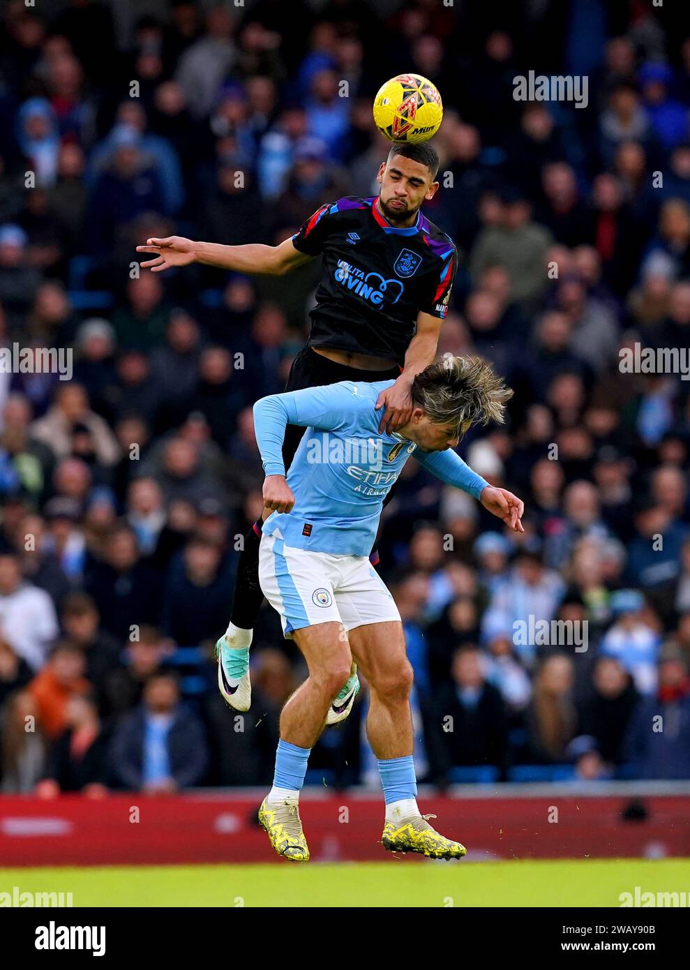 Jack Grealish de Manchester City (en bas) et Brodie Spencer de Huddersfield Town se battent pour le ballon lors du match du troisième tour de la coupe d'Angleterre de football américain au stade Etihad de Manchester. Date de la photo : dimanche 7 janvier 2024. Banque D'Images