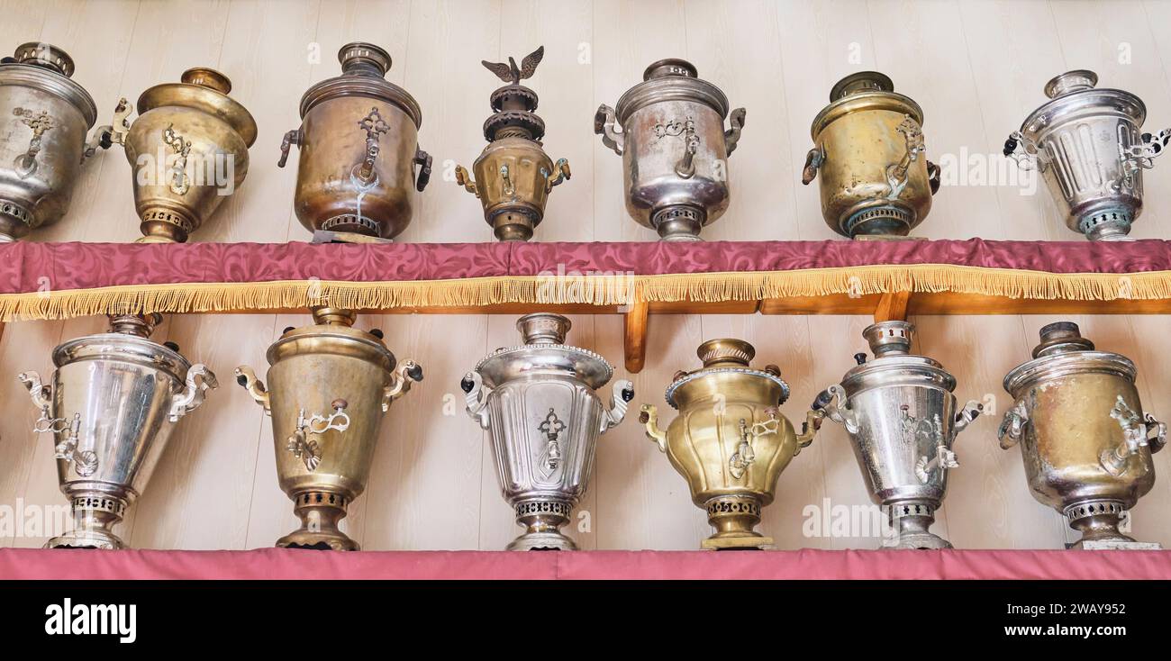 Divers samovars à bois vintage en métal minable, placés sur deux étagères en rangée. Oural, Russie Banque D'Images