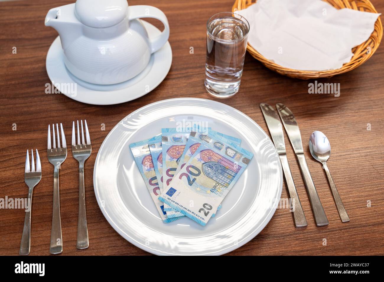 Bavière, Allemagne - 6 janvier 2024 : concept de coût de la nourriture et de gastronomie. Une table couchée avec une assiette blanche avec des billets en euros *** Kosten für Nahrung und Gastronomie Konzept. Ein gedeckter Tisch mit einem weißen Teller mit Euro Geldscheinen Banque D'Images