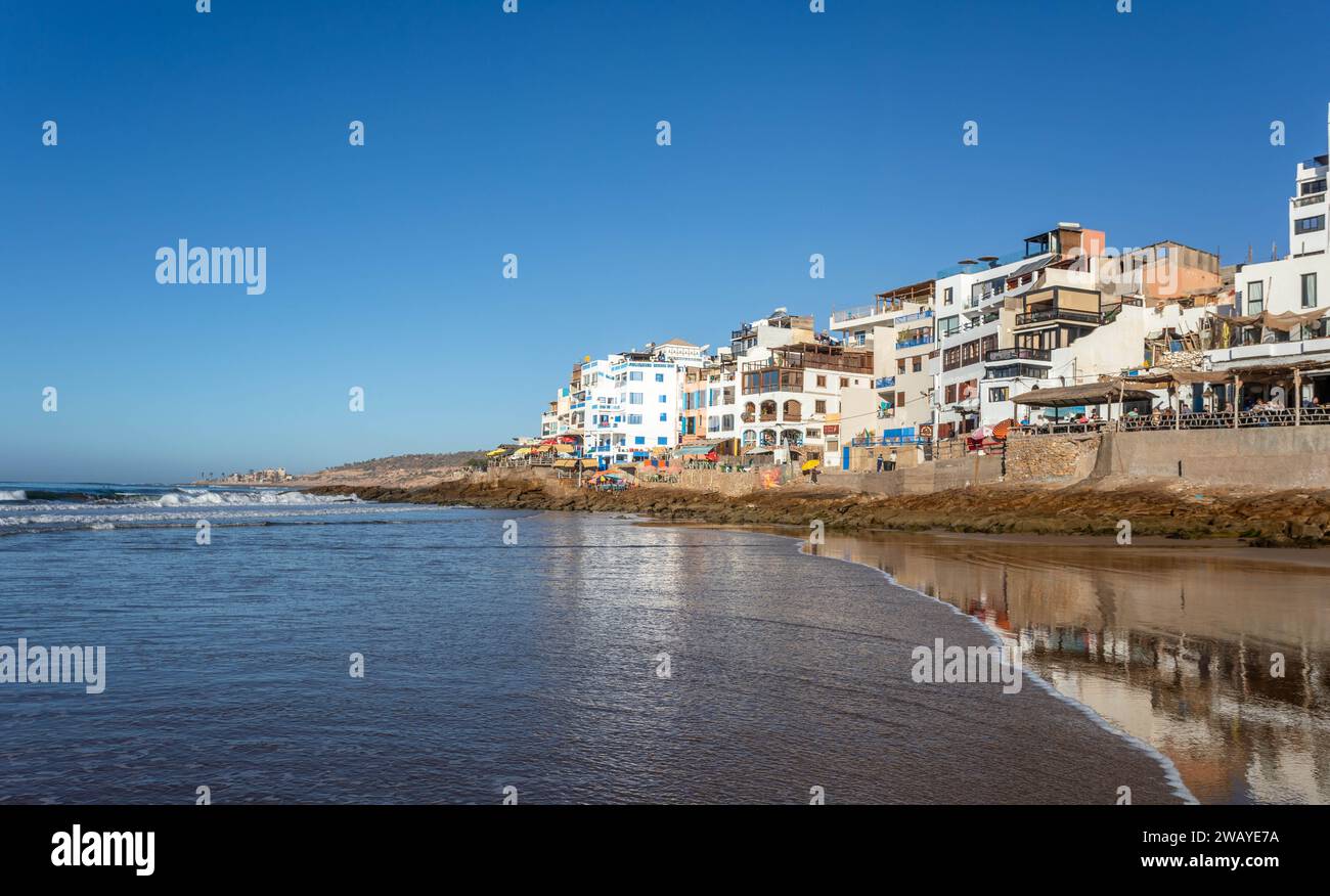 Maisons en front de mer / cafés avec vue sur l'océan Atlantique et les plages dans le village de pêcheurs de Taghazout, Maroc, Afrique du Nord sur une journée ensoleillée Banque D'Images