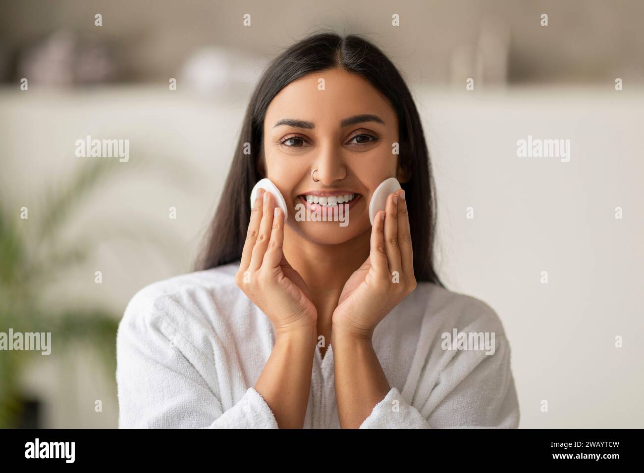 Joyeuse belle femme indienne nettoyant le visage avec des tampons Banque D'Images