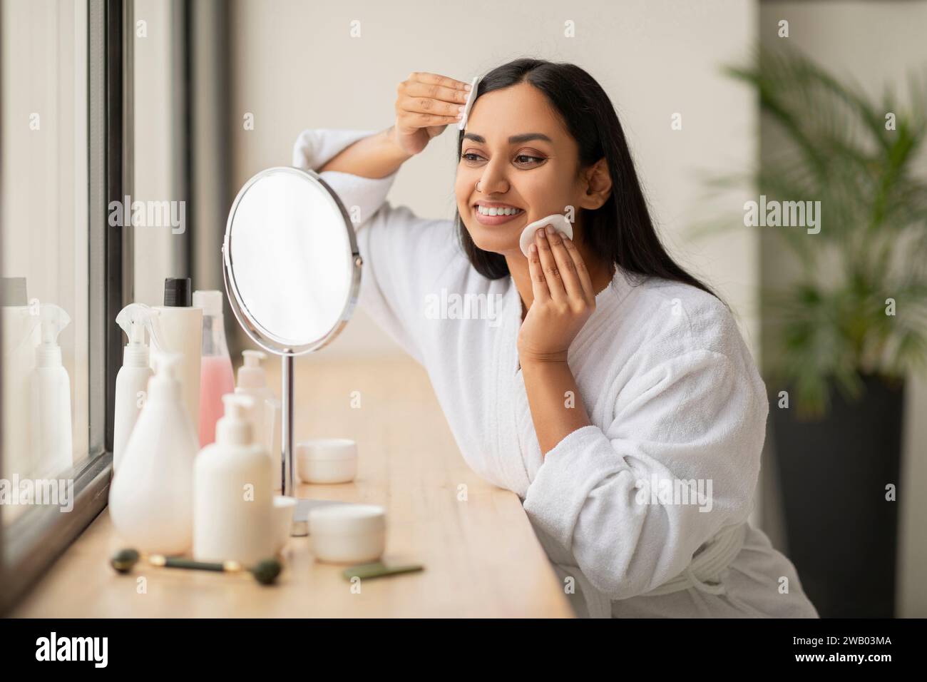 Belle femme indienne souriante nettoyant la peau avec Cotton Pads Banque D'Images