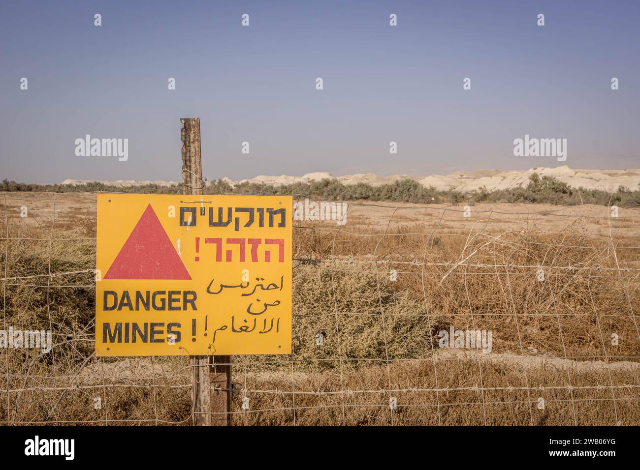 Le signe 'danger Mines!' (En anglais, arabe et hébreu) devant le grand champ de mines en Cisjordanie, territoires palestiniens / Palestine. Banque D'Images