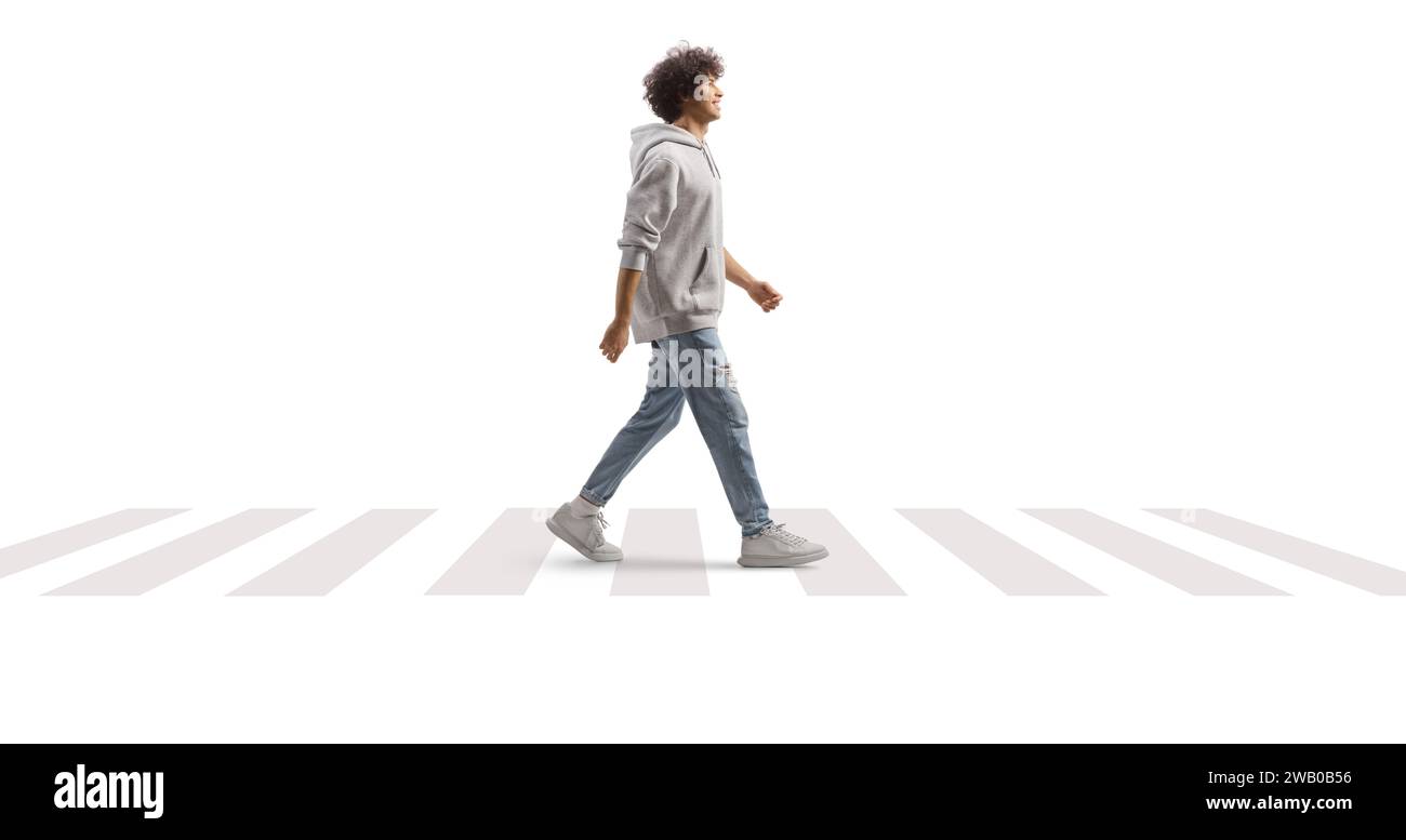 Portrait en longueur d'un grand gars avec les cheveux bouclés marchant à un passage piéton isolé sur fond blanc Banque D'Images