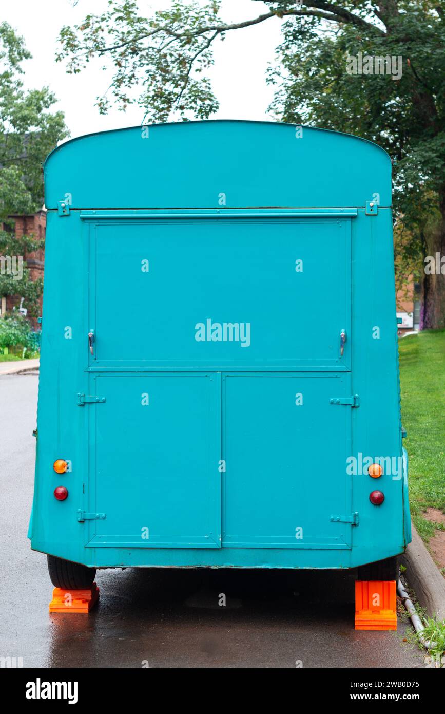 L'arrière d'un camion alimentaire commercial vintage couleur bleu sarcelle garé sur le côté d'une chaussée avec des blocs orange derrière les roues du mobile Banque D'Images
