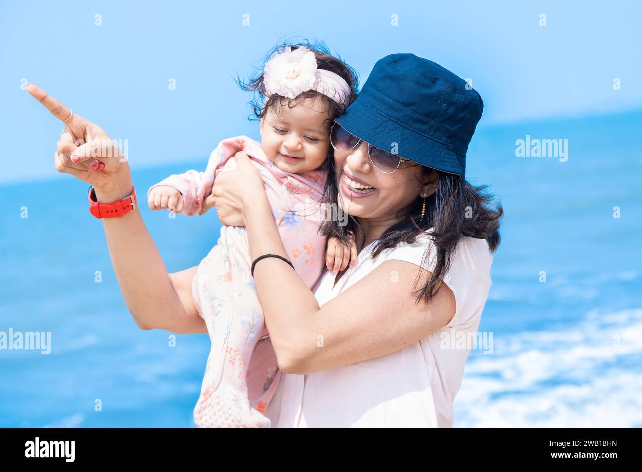 Jeune mère indienne jouant avec sa mignonne petite fille et profitant des vacances d'été sur la plage tropicale. Concept de famille heureuse. Banque D'Images