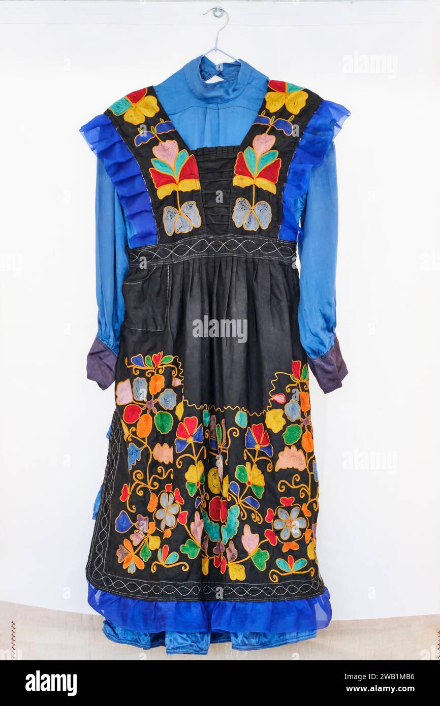 Vêtements traditionnels pour femme tatar festif. Vieille robe bleue et tablier brodé noir avec des motifs floraux complexes colorés lumineux dans le national Banque D'Images