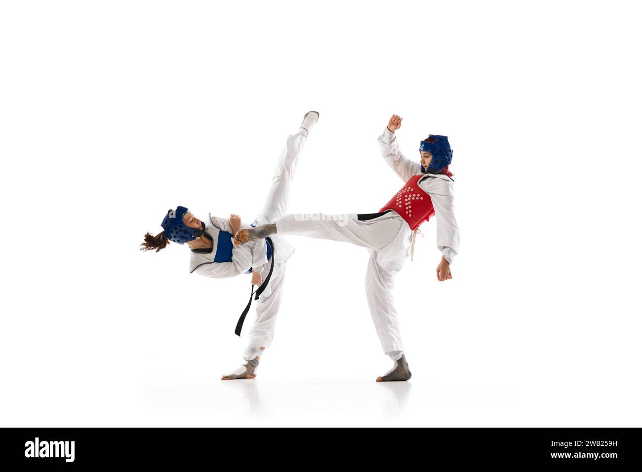 Coup de pied de jambe. Jeune fille, athlètes de taekwondo de compétition en dobok et entraînement de casque isolé sur fond blanc Banque D'Images