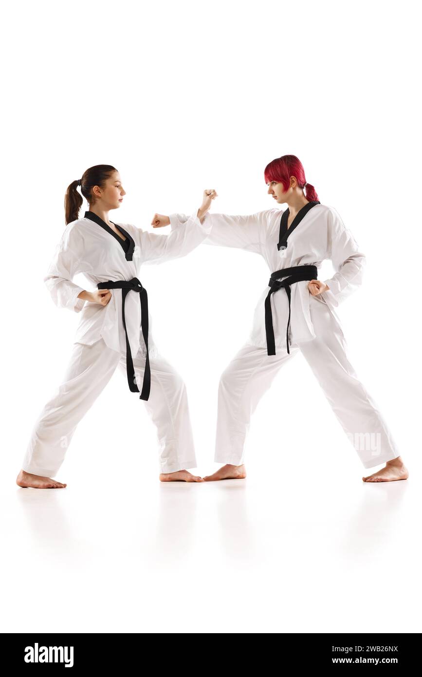 Jeunes filles sportives en kimono et ceinture noire pratiquant karaté, judo, taekwondo cascades isolées sur fond blanc Banque D'Images