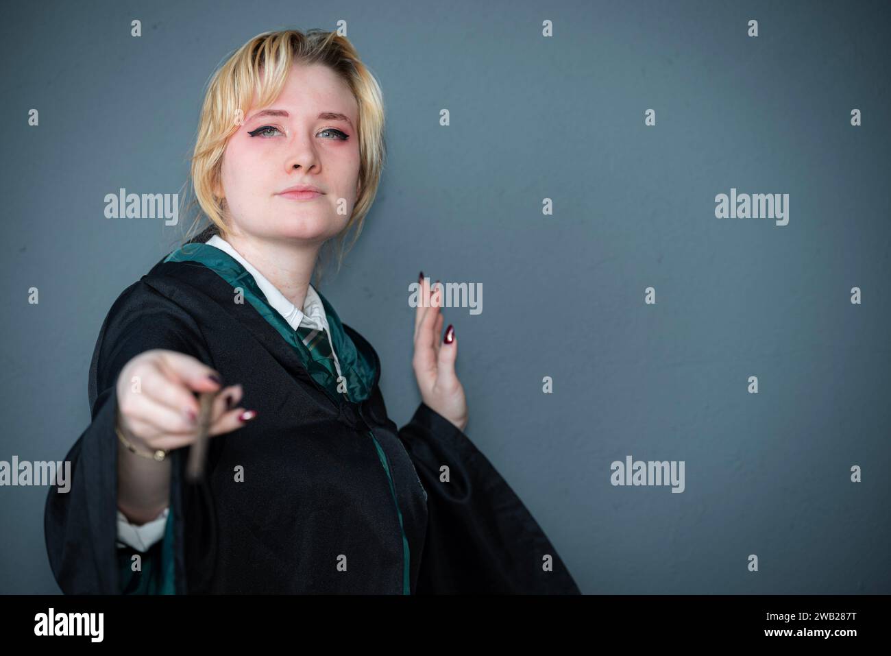 Une cosplayeuse blonde caucasienne habillée comme un sorcier avec une baguette magique Banque D'Images