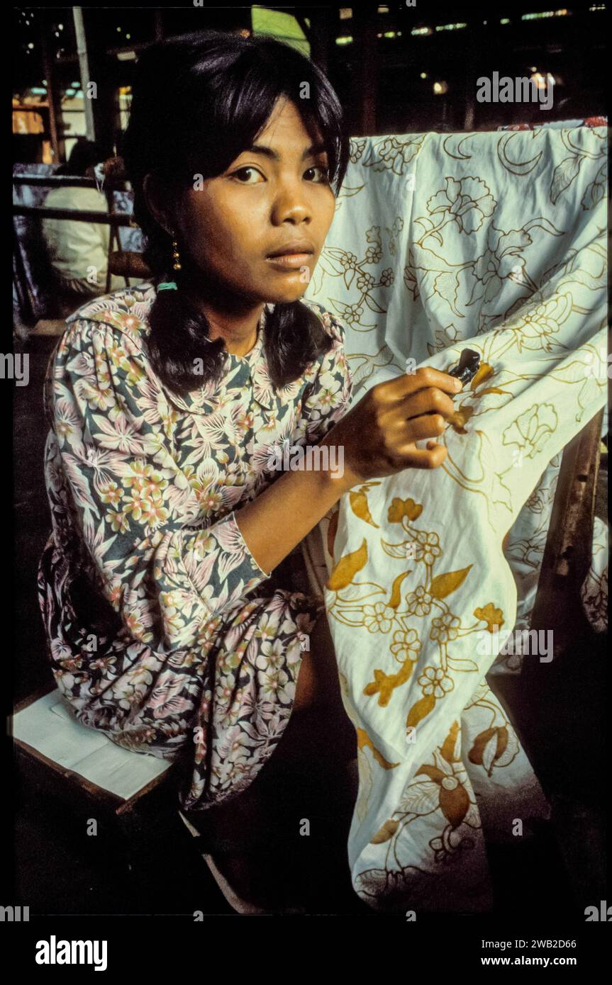 Indonésie, Java - dans une usine de batik, une femme applique de la cire sur un tissu, puis le fait teindre pour qu'il devienne un batik traditionnel. Banque D'Images