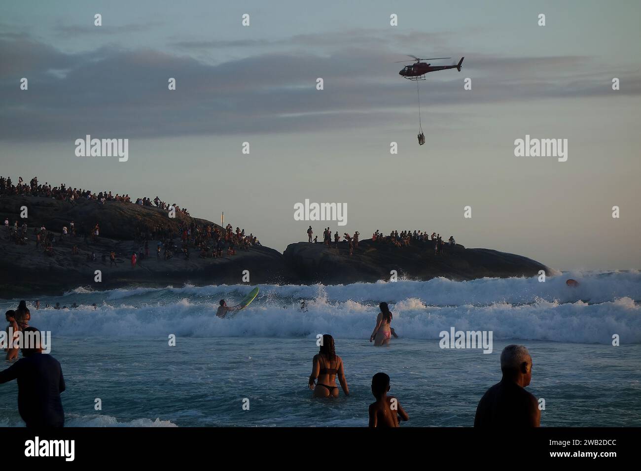 Rio de Janeiro, Rio de Janeiro, Brésil. 7 janvier 2024. L'Air Sea Rescue de Rio de Janeiro a réussi une opération de sauvetage au coucher du soleil sur la plage d'Ipanema, sauvant un nageur en détresse. Dans le contexte des pierres de l'Arpoador, un hélicoptère a transporté la personne secourue devant des centaines de personnes qui se rassemblent tous les jours pour assister aux magnifiques couchers de soleil. Cet incident a souligné l'activité accrue dans les eaux de Rio depuis le début de la nouvelle année, avec une augmentation notable des opérations de sauvetage répondant aux conditions de surf intense. (Image de crédit : © Bob Karp/ZUMA Press Wire) USAGE ÉDITORIAL SEULEMENT! Banque D'Images