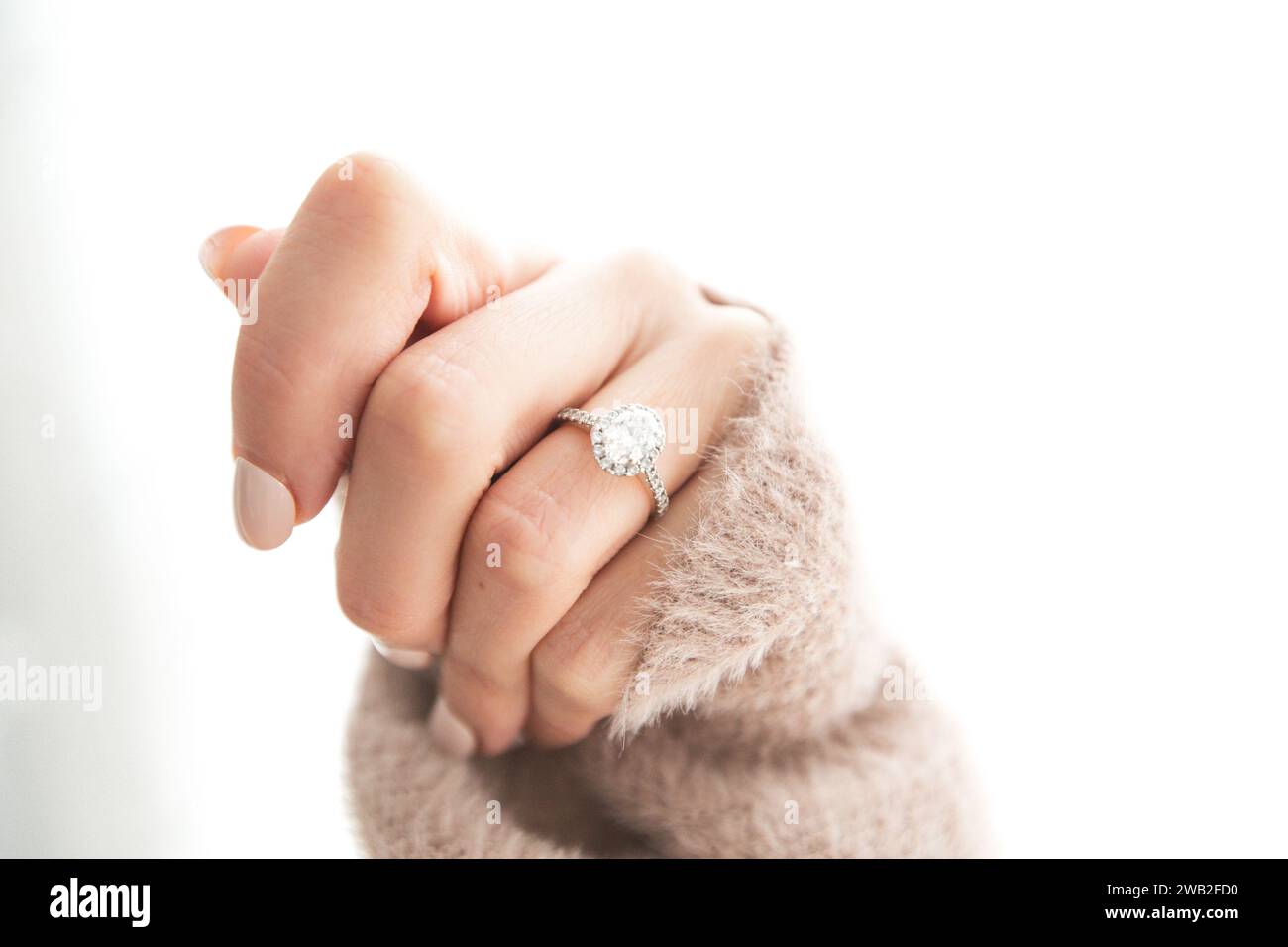 Bague en diamant sur la main fermée de la femme, portant un pull Banque D'Images