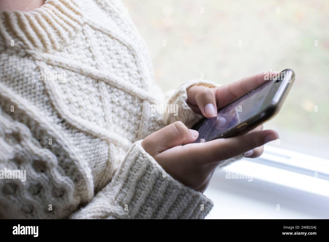 Gros plan des mains d'une adolescente biraciale qui envoient des SMS sur un téléphone portable Banque D'Images