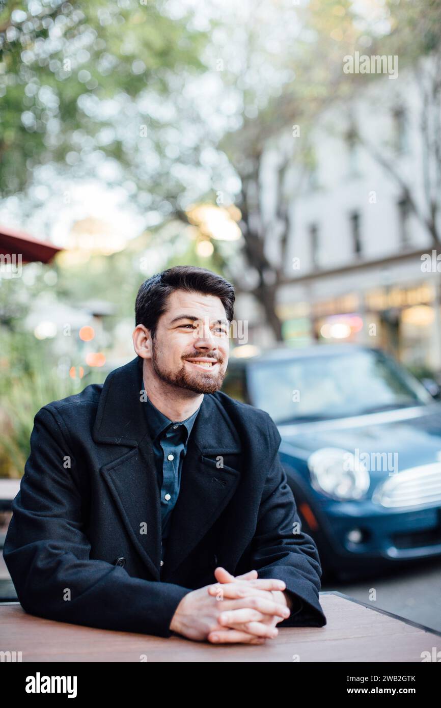 Homme souriant à table attendant la compagnie Banque D'Images