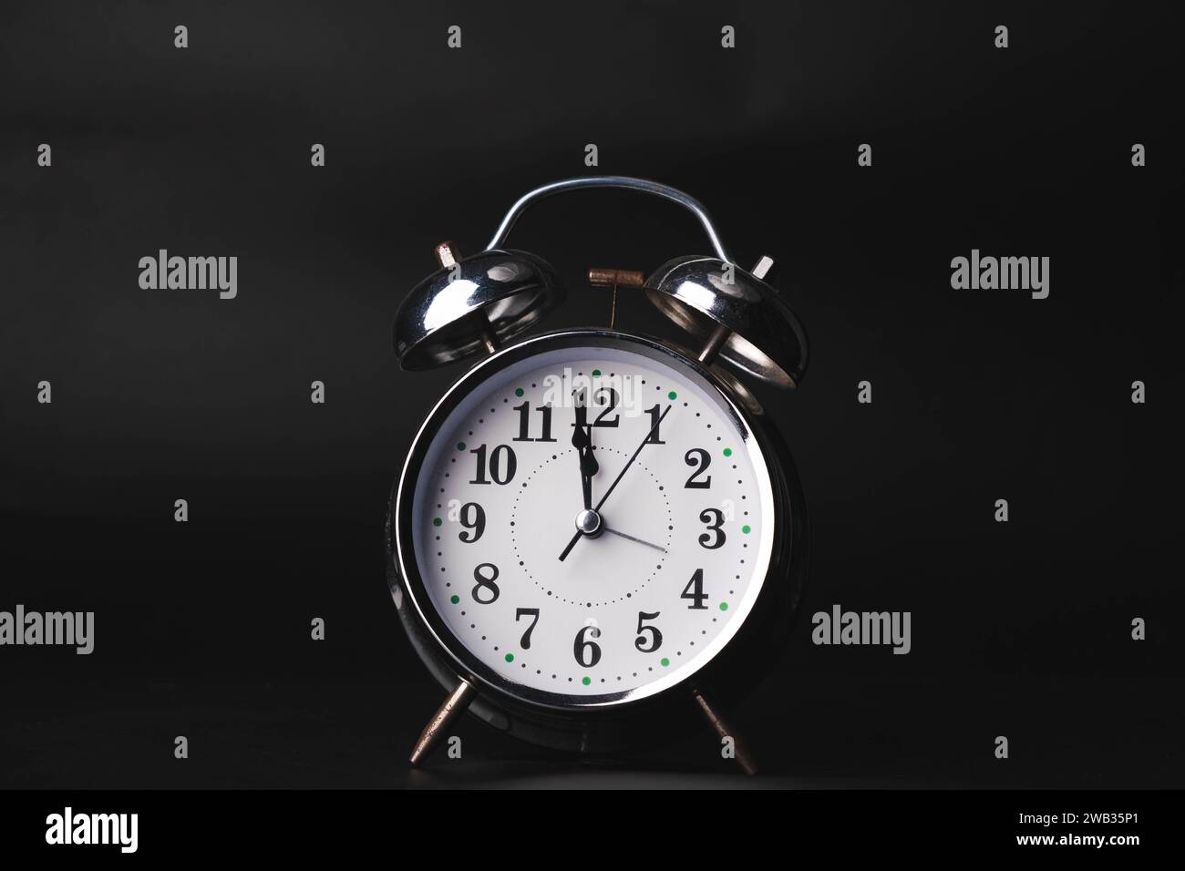 Gros plan d'un cadran de réveil rétro sur fond noir. Les aiguilles de l'horloge se déplacent rapidement, le début du temps 12:00 AM ou 12:00 PM. Banque D'Images