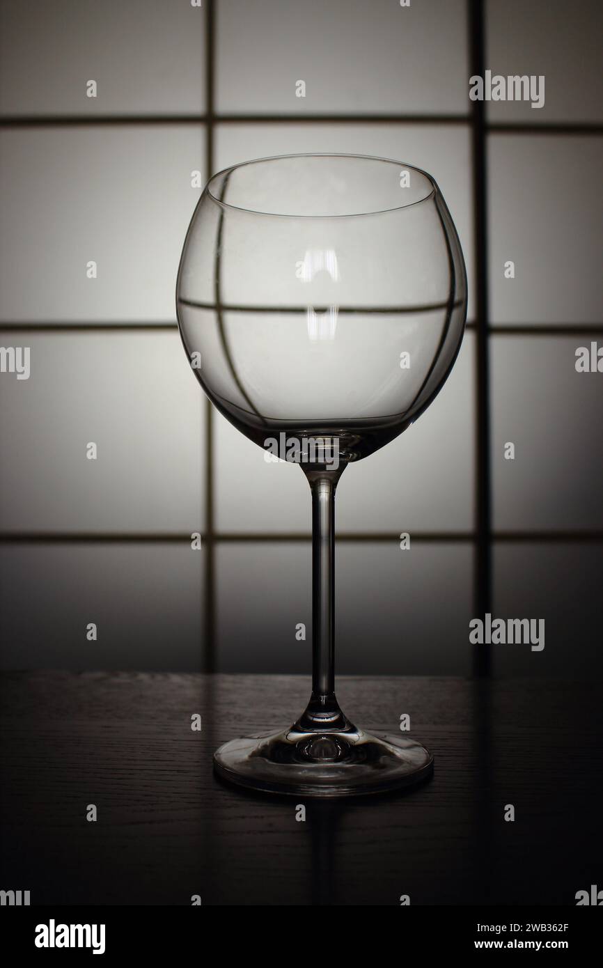 Verre vide pour le vin isolé sur la table sur fond carré. Minimalisme strict nature morte. Noir et blanc monochrome. Banque D'Images