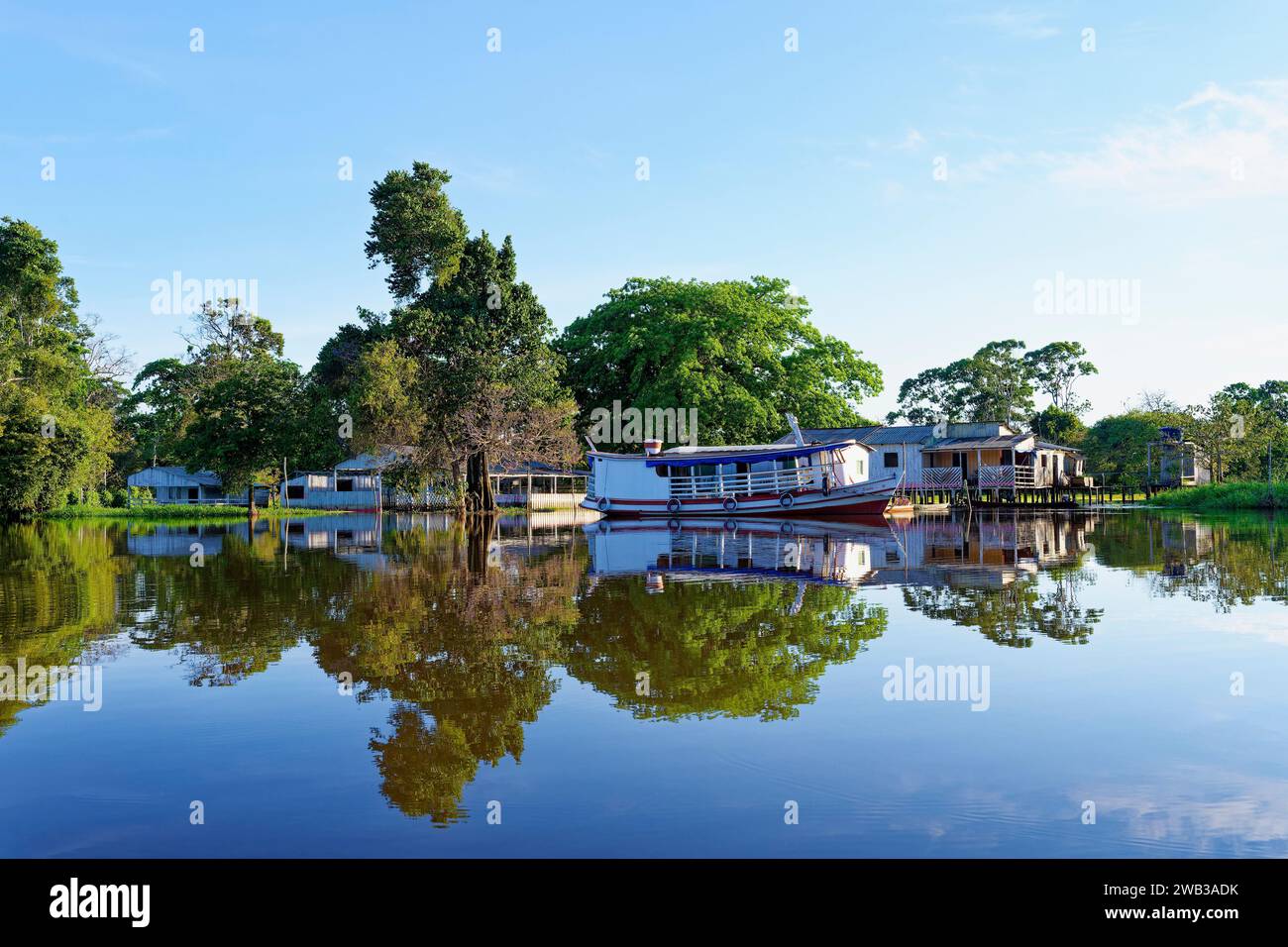 Maisons en bois sur pilotis se reflétant dans le fleuve Amazone, état d'Amazonas, Brésil Banque D'Images