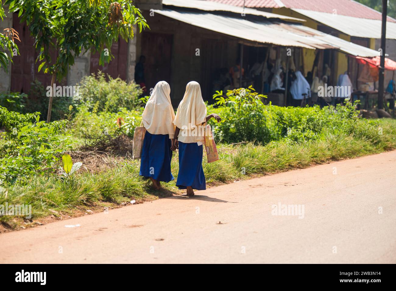 Zanzibar, Tanzanie - 01 mai,2022: Vue sur la rue de la vie quotidienne habituelle des gens de tous les âges se tenant le long de la route sur l'île de Zanzibar. Banque D'Images