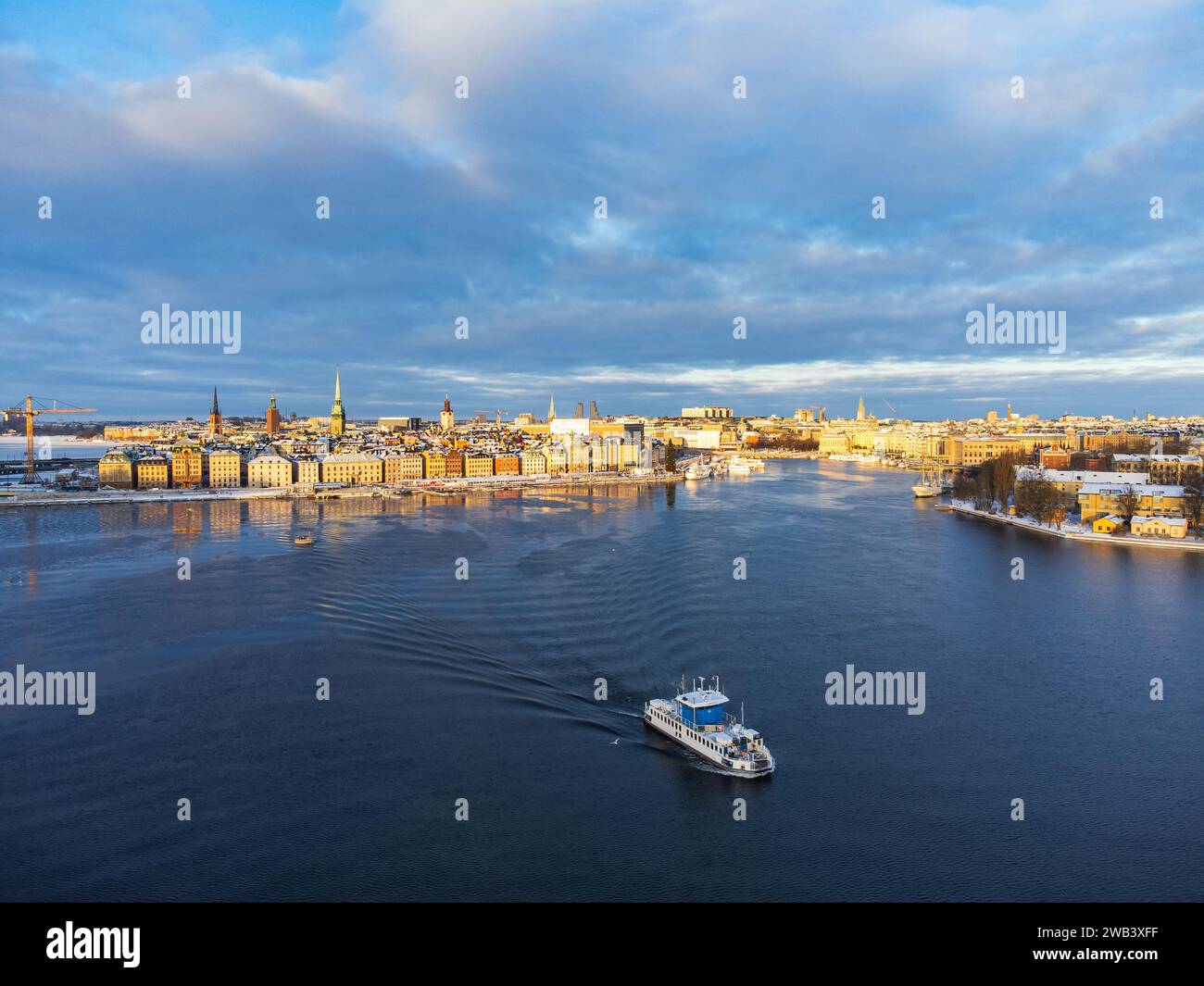 Un bateau de banlieue quittant la vieille ville de Stockholm dans le soleil du matin, l'hiver et la neige, partiellement nuageux, bâtiments historiques médiévaux. Mer Baltique. Banque D'Images