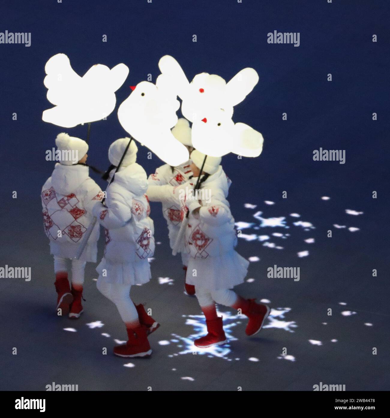 4 FÉV 2022 - Pékin, Chine : performance de flocons de neige où les enfants jouent heureux, tenant des lampes de colombe et des lanternes, laissant des traînées de neige scintillante Banque D'Images