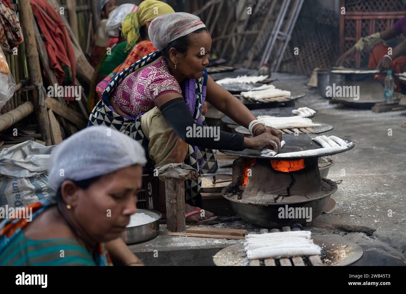 Guwahati, Assam, Inde. 8 janvier 2024. Les femmes font de la pitha traditionnelle assamaise (gâteau de riz) avant le Magh Bihu, également connu sous le nom de festival Bhogali Bihu, le 8 janvier 2024 à Guwahati, Assam, en Inde. Magh Bihu, également connu sous le nom de Bhogali Bihu, est une fête de la récolte célébrée dans l'État indien d'Assam. Crédit : David Talukdar/Alamy Live News Banque D'Images