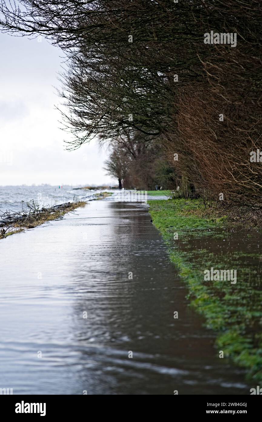 Niveau d'eau élevé en raison des fortes pluies et de la tempête, des vagues du lac Markermeer coulant sur la digue de pierre et le sentier pédestre et inondant le parc de la ville Banque D'Images