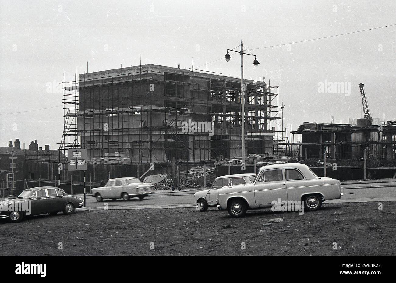 Années 1960, historique, un nouveau centre civique pour le logement et les services sociaux et la régie régionale de la santé en construction à West Street, OIdham, Manchester, Angleterre, Royaume-Uni. Entrepreneur principal, Gerrard de Swinton, Manchester. Voitures de l'époque garées sur le terrain de déchets en face. Au milieu des années 70, un nouveau bloc de tour moderne - une tour de 15 étages - a été ajouté au bâtiment original vu ici. Banque D'Images