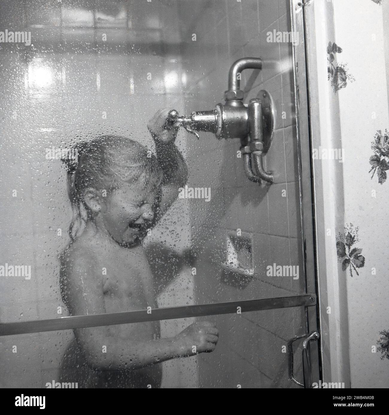 1991, historique, une jeune fille excitée debout dans un cubicule, profitant de l'eau chaude d'une douche puissante, Angleterre, Royaume-Uni. Banque D'Images