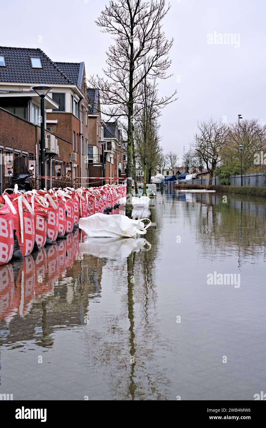 Big Bags et sacs de sable le long de la route inondée par la tempête Henk pour protéger la rue résidentielle avec des maisons et des immeubles d'appartements, pays-Bas Banque D'Images
