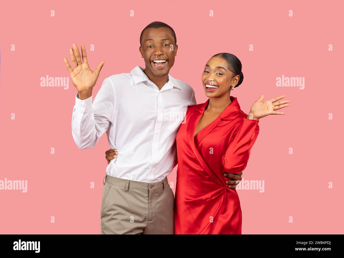 Joyeux couple noir agitant les mains avec des sourires lumineux, fond rose Banque D'Images