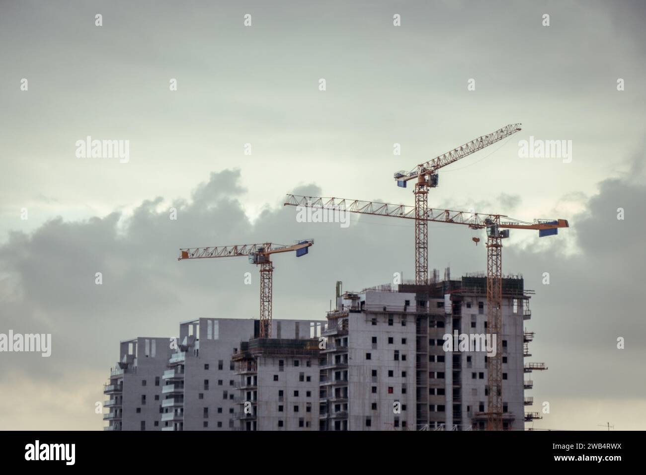 Trois grues tour au-dessus du projet d'immeuble d'appartements. Construction de condominiums. Coucher de soleil, heure dorée, noir et blanc, avec des nuages Banque D'Images