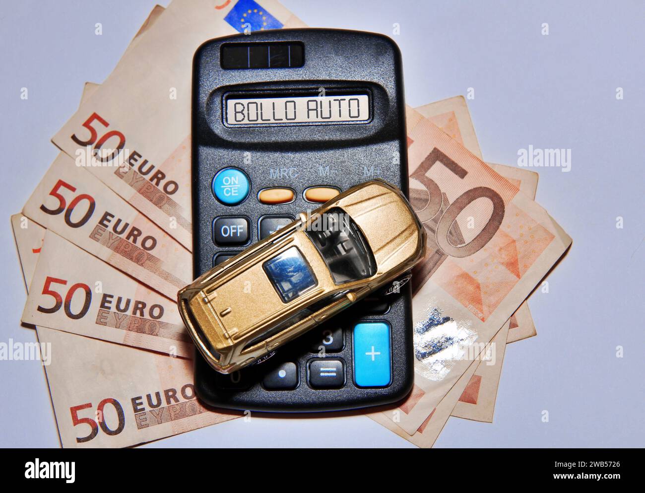 Jouet de voiture sur une calculatrice avec des billets de banque en euros avec le texte «Bollo Auto» concept de taxe italienne . Banque D'Images